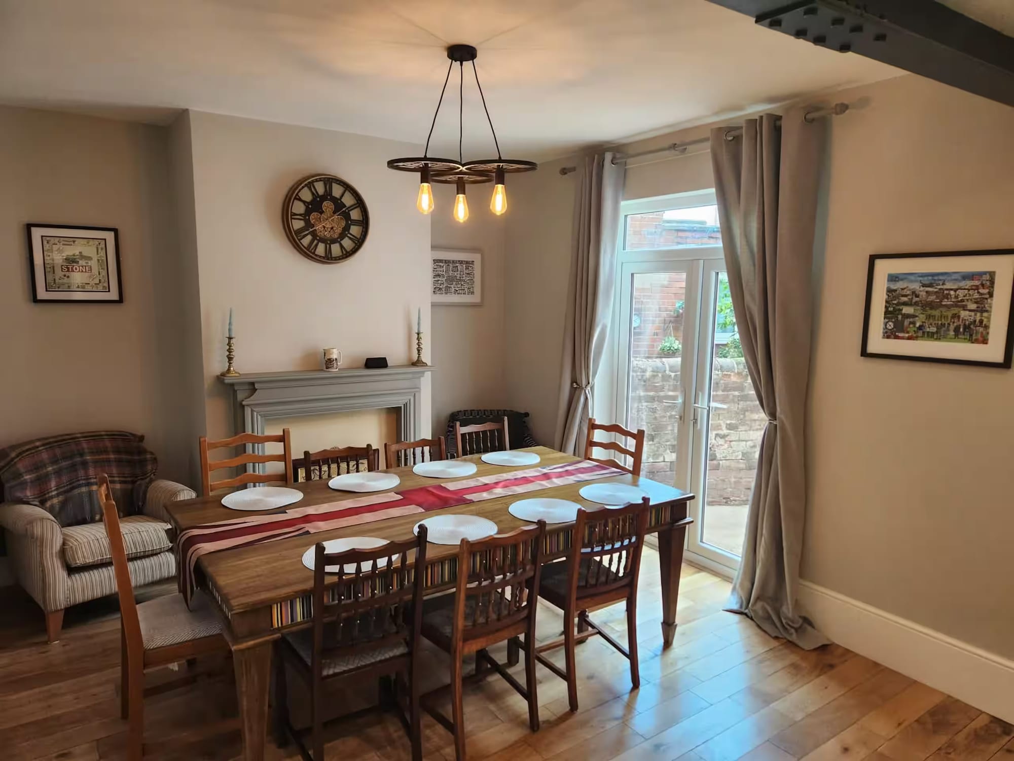 Dining room with a long wooden table set for eight, a fireplace and French doors to the garden